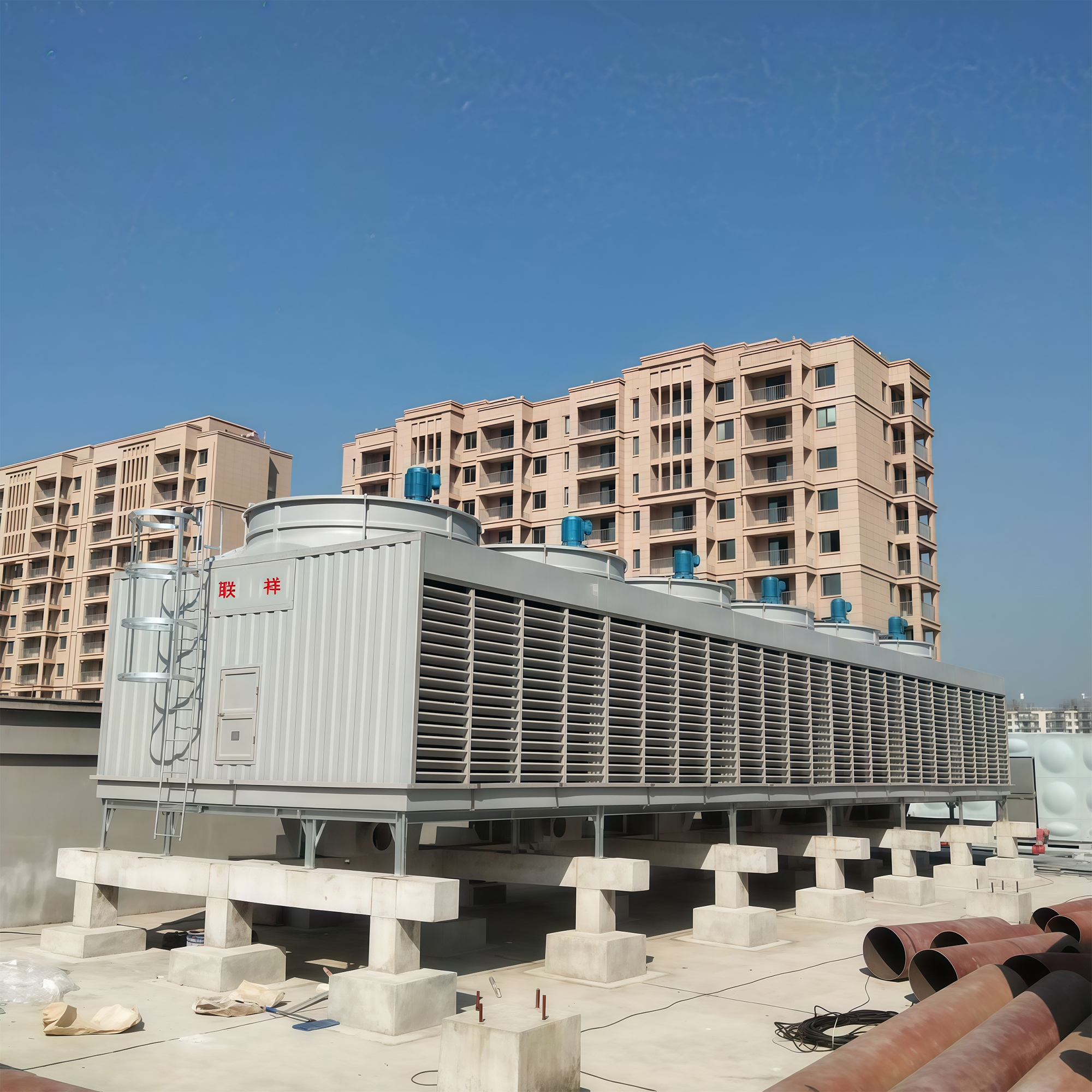 Rooftop crossflow cooling tower with a row of fans beside residential buildings